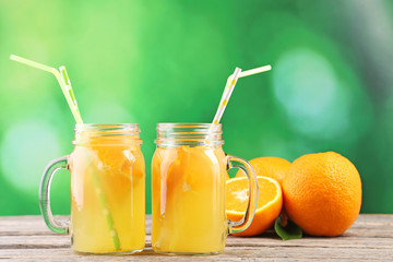 Obraz na płótnie Canvas Glass jars with orange juice on wooden table