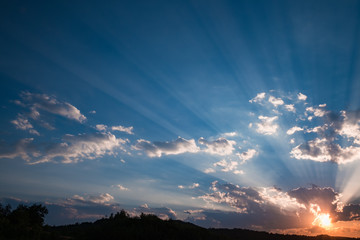 Sunset sky with sun beams bursting through the dark clouds. Conceptual meditation background. Hope,...
