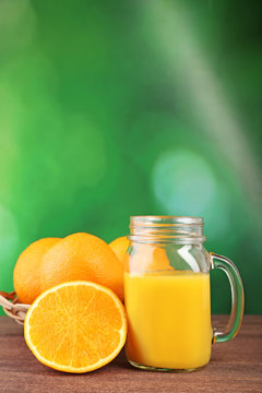 Glass jar with orange juice on wooden table