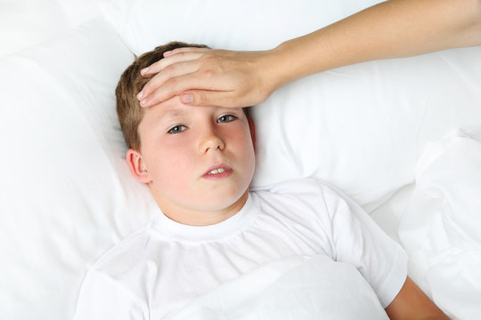 Sick boy lying in white bed