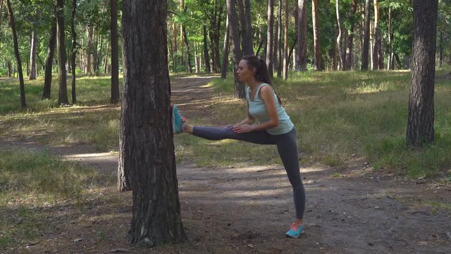 Beautiful young brunette doing a dumbbell for stretching. The emphasis of the foot in the tree. Sexual fitness for fitness.