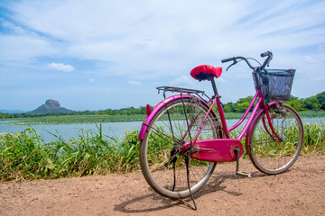 Fototapeta premium The bicycle stands on a village road at Thalkote lake near Sigiriya. Renting a bicycle and cycling around Sigiriya village is the most popular way among the tourists 