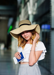 Pretty girl in a wide-brimmed hat with the passport and tickets in a hand.