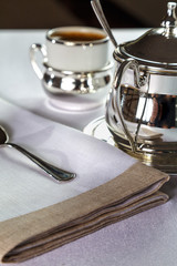 coffee in a beautiful mug with a silver holder and silver sugar bowl