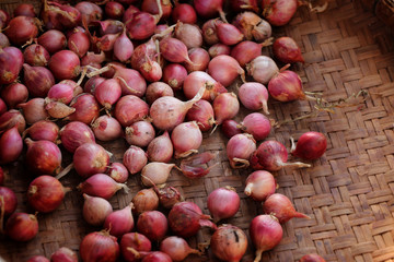 organic small red onion on bamboo basket at local farmer's market in Thailand.