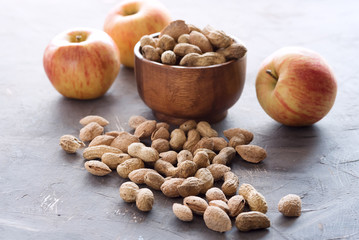 Wooden bowl with unpeeled nuts and dried fruit Apples Dried fruit Peanuts Almond lying on background