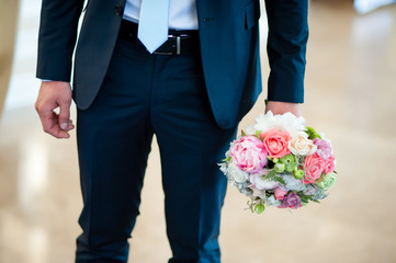 the groom holds the wedding bouquet.