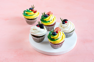 Tasty cupcakes with cream cheese topped with fresh berries Pink background Beautiful cupcakes decorated with colorfull cream cheese Copy space