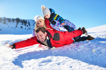 Fototapeta na wymiar happy young family playing in fresh snow at beautiful sunny winter day outdoor in nature
