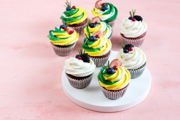 Tasty cupcakes with cream cheese topped with fresh berries Pink background Beautiful cupcakes decorated with colorfull cream cheese Copy space