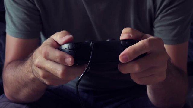 Video game console controller in male hands, man playing entertaining game at home