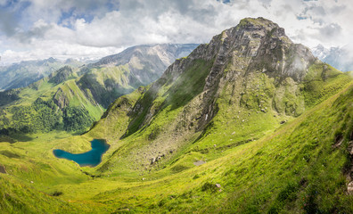 Fototapeta premium Mountain landscape in the alps with green pastures and mountain lake