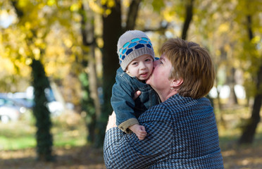 grandmother kiss grandson in a park in autumn