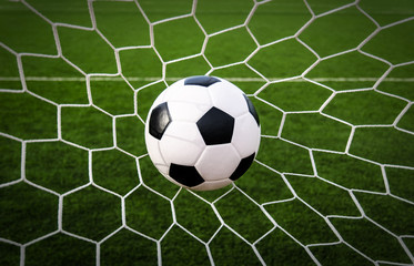 Fototapeta na wymiar Soccer football in Goal net with green grass field.