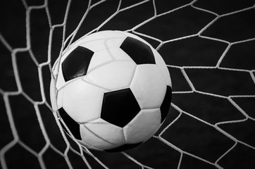 Fototapeta premium Soccer football in Goal net with green grass field.