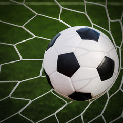 Fototapeta na wymiar Soccer football in Goal net with green grass field.