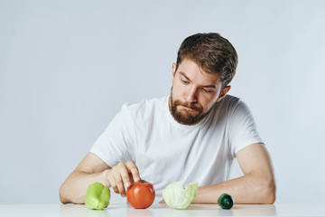 Young guy with beard on white isolated background, vegetables, vegan, healthy eating right