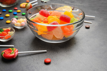 Bowls with delicious candies on grey background