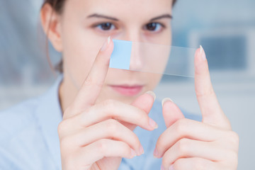 student girl with glass empty microscope slide in hand