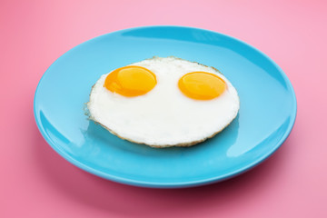 Plate with delicious sunny side up eggs on colour background