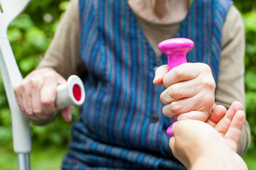 Elderly woman holding pink dumbbells close up