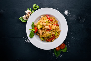 Pasta with chicken fillet, parmesan cheese and mushrooms and basil. On a black wooden surface. Free space for your text. Top view.