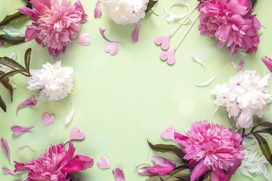 Frame of peonies and decorative hearts on green background. Place for the text.