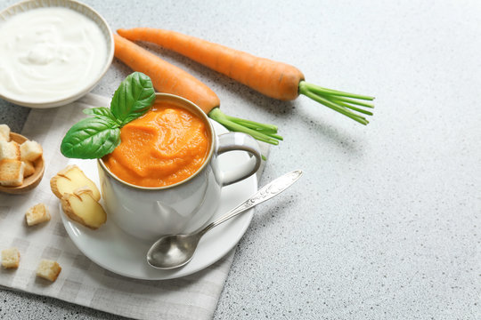 Composition with delicious carrot soup and fresh ginger on table