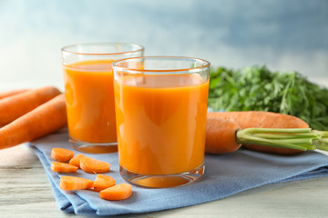 Two glasses of homemade carrot juice with vegetables on wooden table