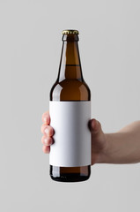 Beer Bottle Mock-Up. Blank Label - Male hands holding a beer bottle on a gray background