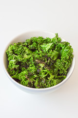 Oily kale chips in big bowl on white background. Kale salad. Organic food