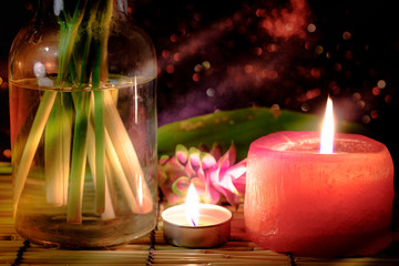 Obraz na płótnie Canvas Pink flower of Pink Siam Tulip or Curcuma sessilis flower in vase and burning candle light with light Pink bokeh background. Concept of peace, meditation, hope and relaxation