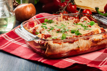 Traditional mexican enchiladas with chicken meat, spicy tomato sauce and cheese in heat resistant dish