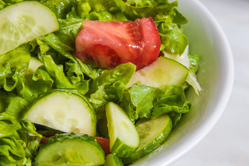 Fresh salad. Tomato, cucumber and greens in white bowl