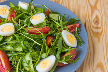 Fresh green salad with arugula, tomatoes, eggs and cucumber