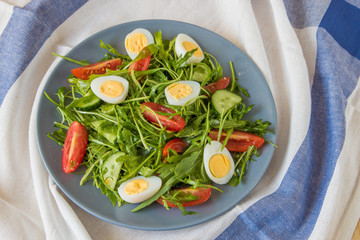 Fresh green salad with arugula, tomatoes, eggs and cucumber