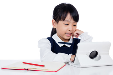 Asian Chinese little girl in uniform studying with tablet computer