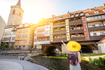 Young woman tourist in yellow hat standing back on the famous Merchants bridge background in Erfurt...