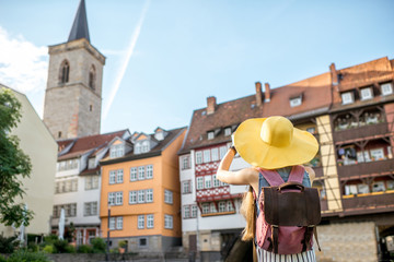 Young woman tourist in yellow hat standing back on the famous Merchants bridge background in Erfurt...