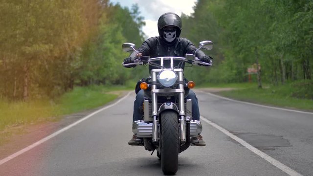 Experienced biker riding motorcycle on asphalt road.