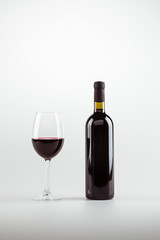 close-up view of red wine in glass and bottle isolated on white
