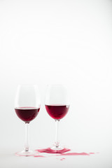 close-up view of wineglasses with red wine and wine spilled isolated on white