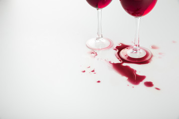 close-up view of wineglasses with red wine and wine spilled isolated on white