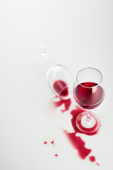 close-up view of red wine in glasses and spilled out isolated on white