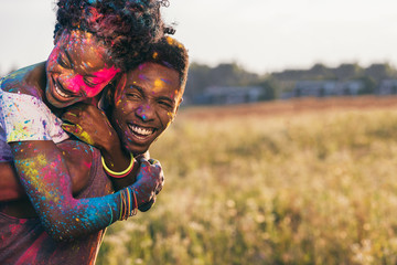 portrait of happy african american couple piggybacking at holi festival - Powered by Adobe