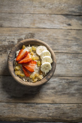 oatmeal porridge with strawberry and banana in wood bowl