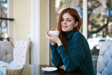 Young beautiful woman drinks coffee in a cafe