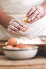 Obraz na płótnie Canvas Senior woman adding egg to pastry