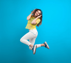 Teenage girl jumping holding headphones