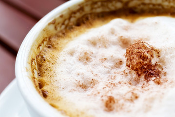 Macro view of cappuccino coffee cup on wooden table